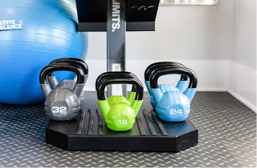 Three kettlebells of different weights are placed on a black stand.