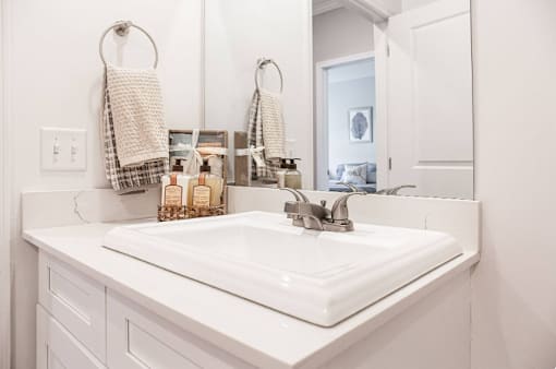 A white bathroom sink with a white counter top and a white cabinet.