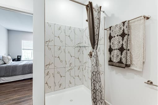A bathroom with a shower curtain and a towel hanging on the wall.
