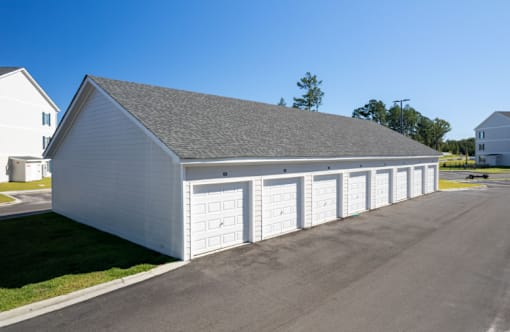 A large white garage with a grey roof and four doors.