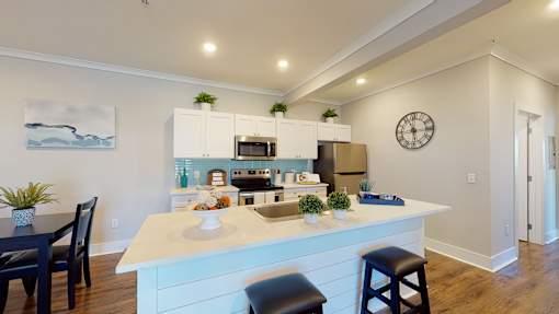 A kitchen with a white island and a painting of a boat on the wall.