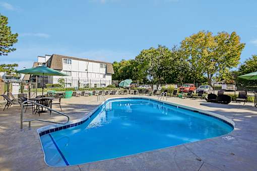 A large outdoor swimming pool surrounded by chairs and umbrellas.