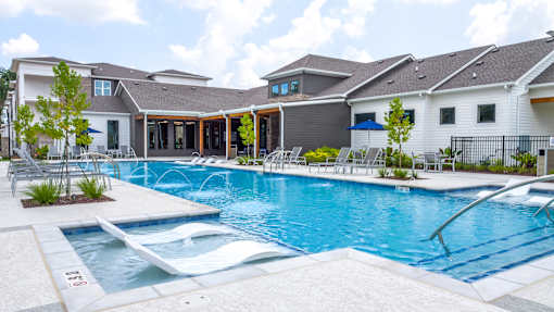 A large outdoor swimming pool with a slide and loungers.