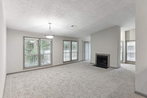 A spacious living room with a fireplace and large windows.