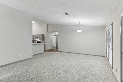 A spacious room with a carpeted floor and a ceiling fan.