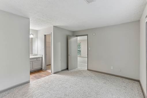 A spacious room with a carpeted floor and a door leading to a balcony.