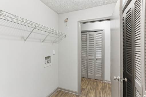 A white room with a door and a shelf.