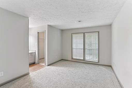 A room with a carpeted floor and a window with blinds.