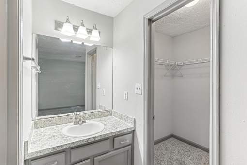 A bathroom with a sink, mirror, and a walk-in shower.