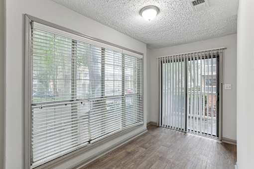 A room with a sliding glass door and a window with blinds.