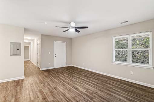 A room with a ceiling fan and a window with a view of trees.