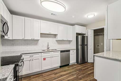 A kitchen with white cabinets and a black counter top.