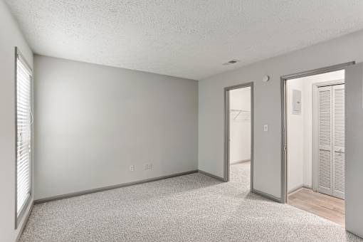 A room with a carpeted floor and a door leading to another room.