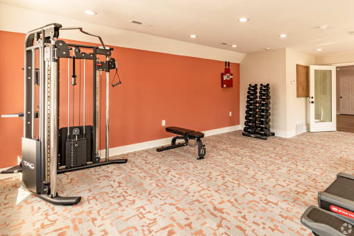a home gym with a red wall and exercise equipment