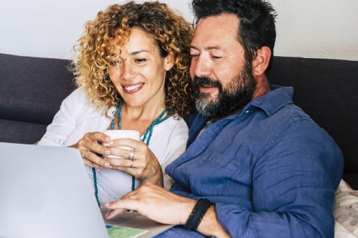 a couple sitting on a couch looking at a laptop