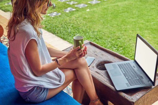 a woman sitting on a bench with a laptop and a cup of coffee