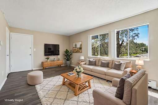 A living room with a brown couch, a coffee table, and a large window.