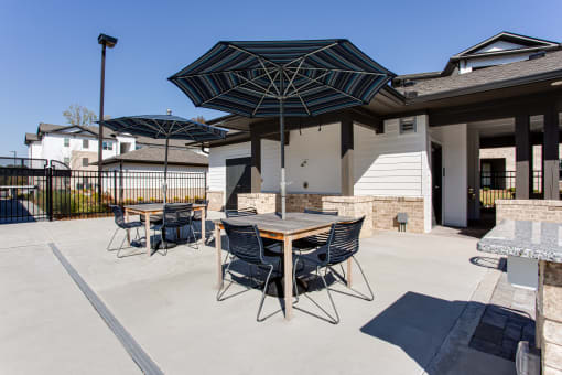 a patio with tables and chairs under umbrellas