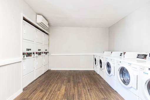 A laundry room with a row of washing machines.