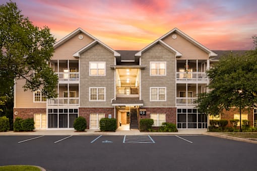 A large apartment building with a parking lot in front.