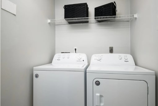 a white laundry room with two washes and a dryer