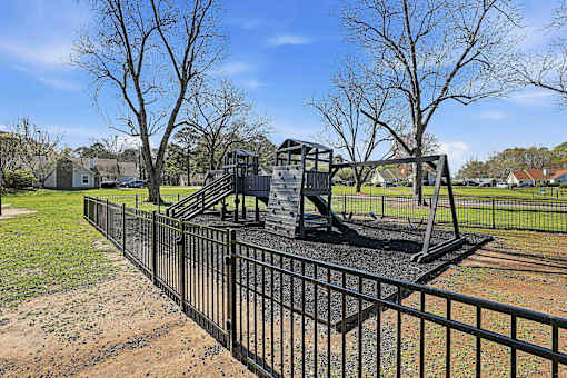 A playground with a swing set and a fence.