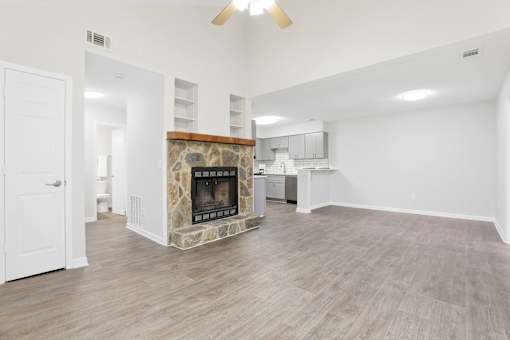 A living room with a stone fireplace and wood flooring.