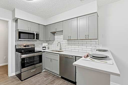 A kitchen with a white counter top and grey cabinets.