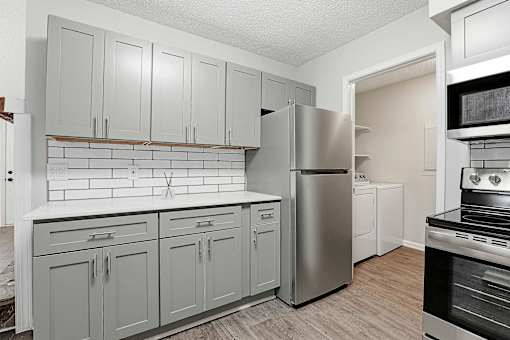 A kitchen with a refrigerator, oven, and cabinets.