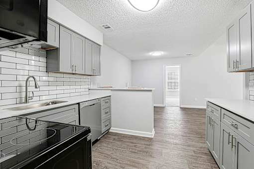 A kitchen with black appliances and white cabinets.
