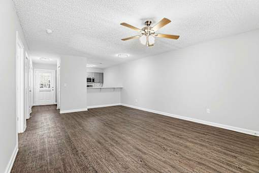 A room with a ceiling fan and wooden flooring.