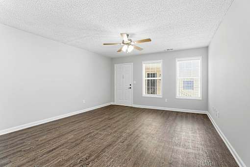 A room with a ceiling fan and wooden flooring.