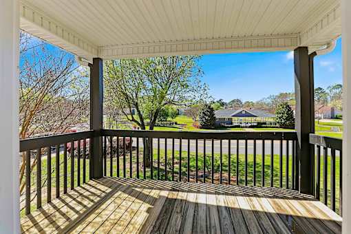 A view from a porch looking out at a green lawn and houses.