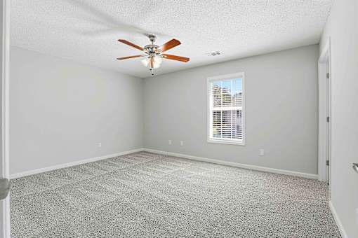 A room with a ceiling fan and a window with blinds.