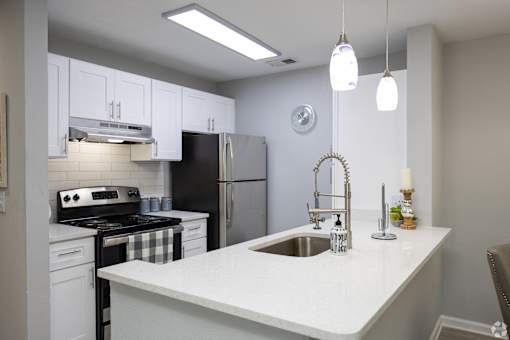 A kitchen with a black refrigerator and white cabinets.