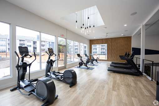 A gym with treadmills, exercise bikes and a wooden floor.