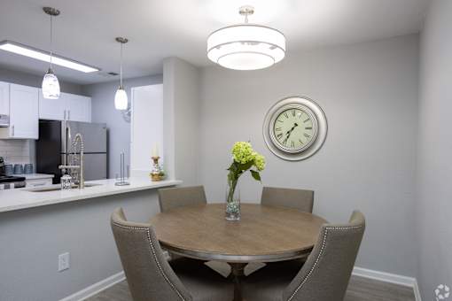 A dining room with a table set for two and a clock on the wall.