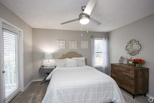 A bedroom with a bed, nightstand, and a dresser.