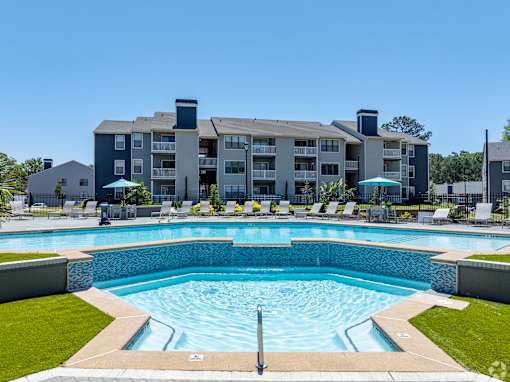 A large swimming pool in front of a multi-story apartment building.