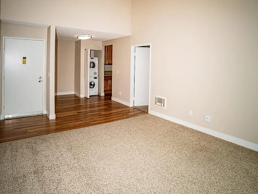an empty living room with wood floors and white walls