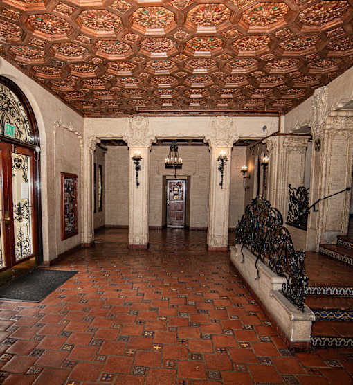 A hallway with a tiled floor and a ceiling with a decorative pattern.