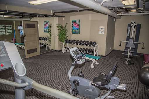 A gym with a variety of equipment including a treadmill, weights, and a bench press.