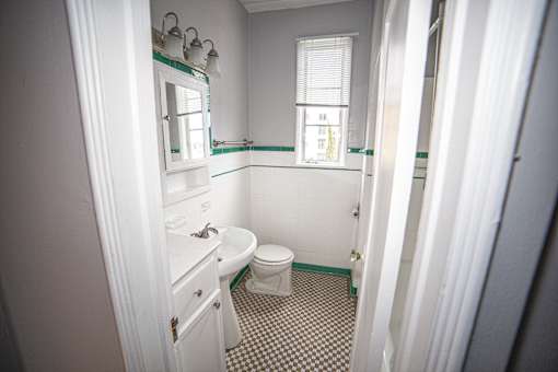 A bathroom with a toilet, sink, and mirror.