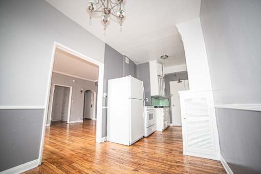 A kitchen with white appliances and wooden floors.