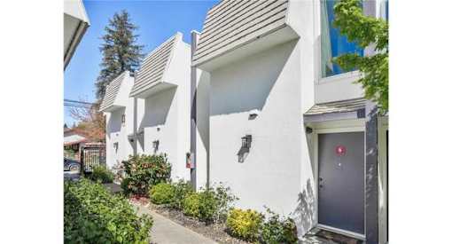 a white building with a gray door next to a sidewalk