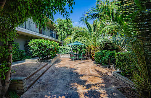 a patio with a table and chairs and a umbrella in front of a building