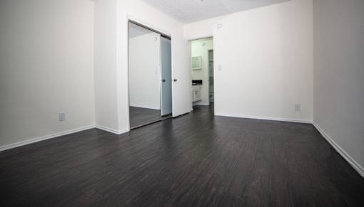 a bedroom with a hardwood floor and white walls