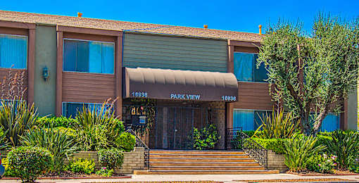 a brown building with a tan awning and stairs in front of it
