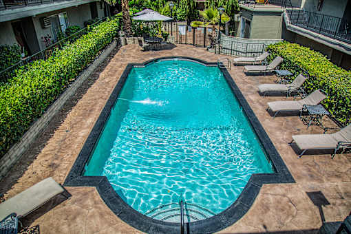 a swimming pool with lounge chairs and umbrellas in front of a building