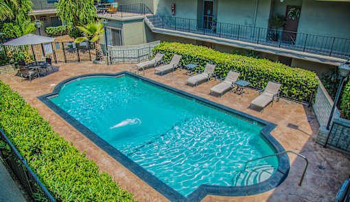 a swimming pool with lounge chairs and umbrellas in front of a hotel